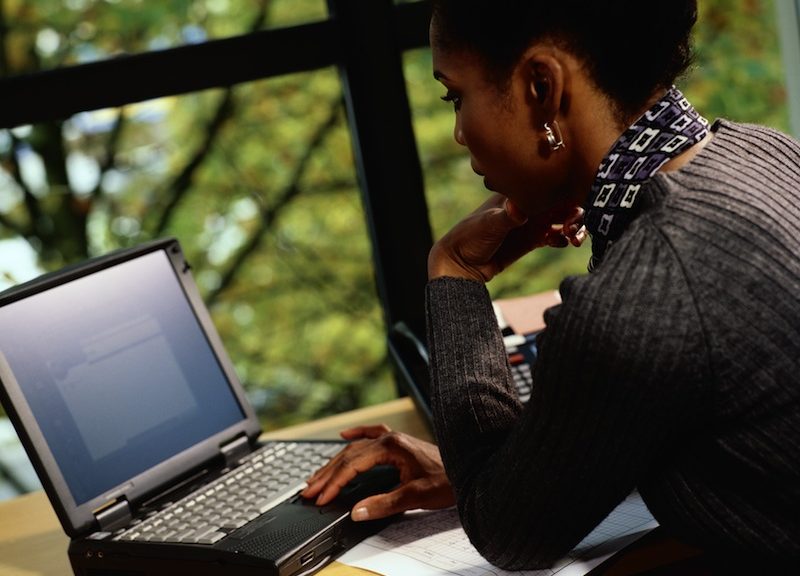 Businesswoman working on laptop, side view