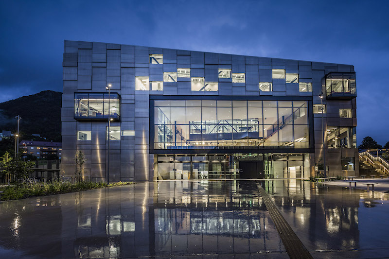 Visibile anche dall’esterno, la grande Project Hall al piano primo è il cuore dell’edificio - vista notturna del prospetto d’ingresso © Tomasz Majewski Photography